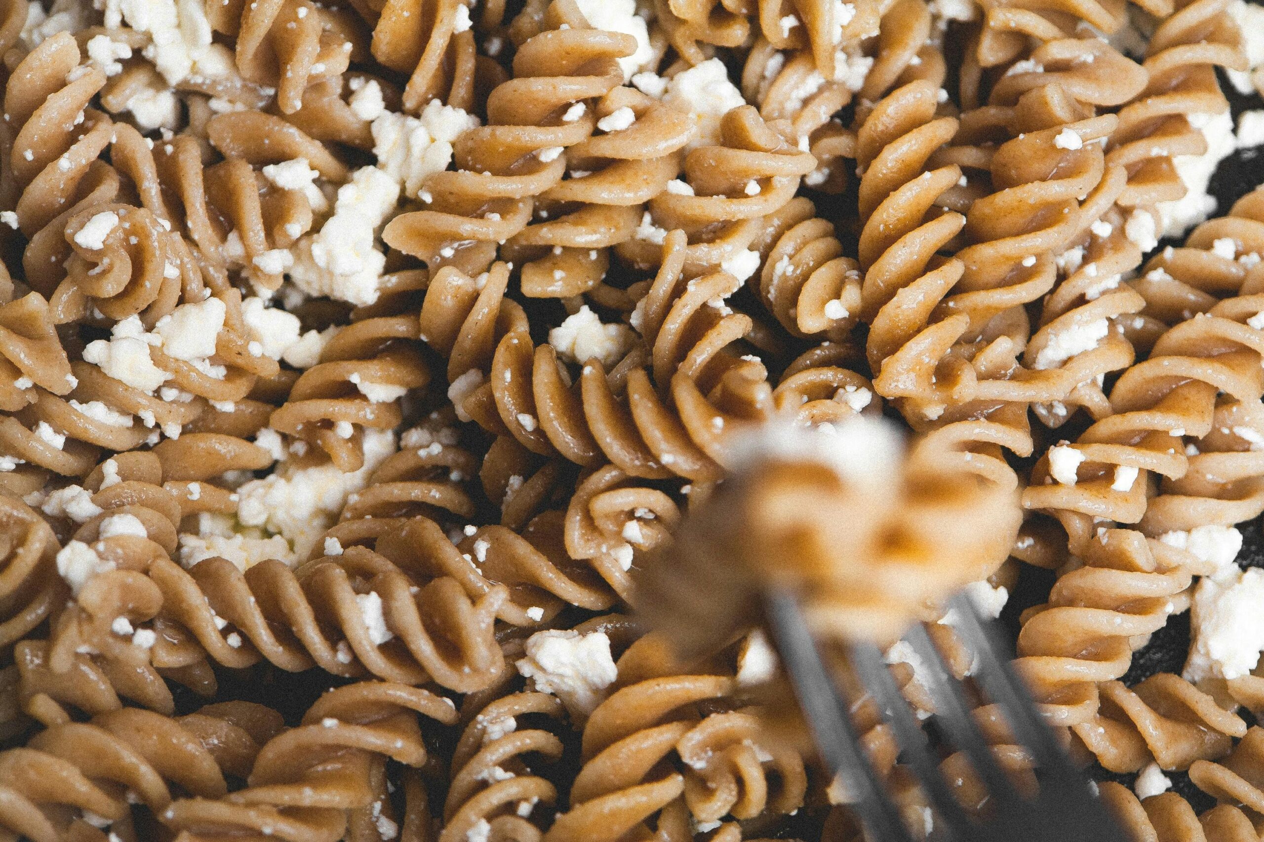 Delicious whole wheat pasta drizzled with white cheese crumbles. Perfect for food enthusiasts.