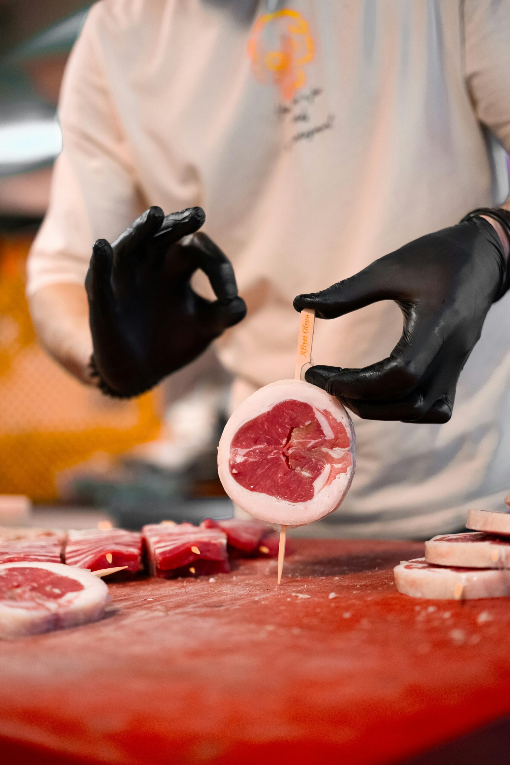 A butcher skillfully preparing fresh red meat slices with precision in a kitchen setting.