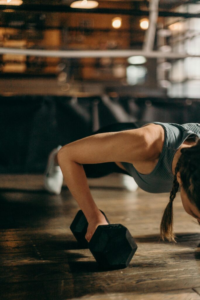 pexels-photo-4753996-4753996 Fit woman doing a dumbbell push-up in a gym, highlighting strength and fitness training.