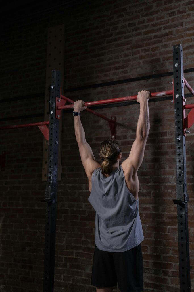 pexels-photo-7671462-7671462 Adult man in activewear doing pull-up exercise on bar at the gym, focused on fitness and strength training.