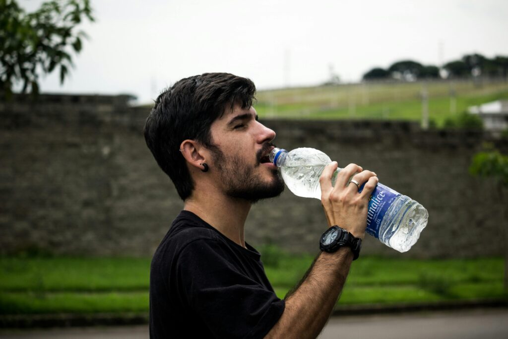 pexels-photo-907865-907865 A young man drinks bottled water outside, staying hydrated and refreshed.