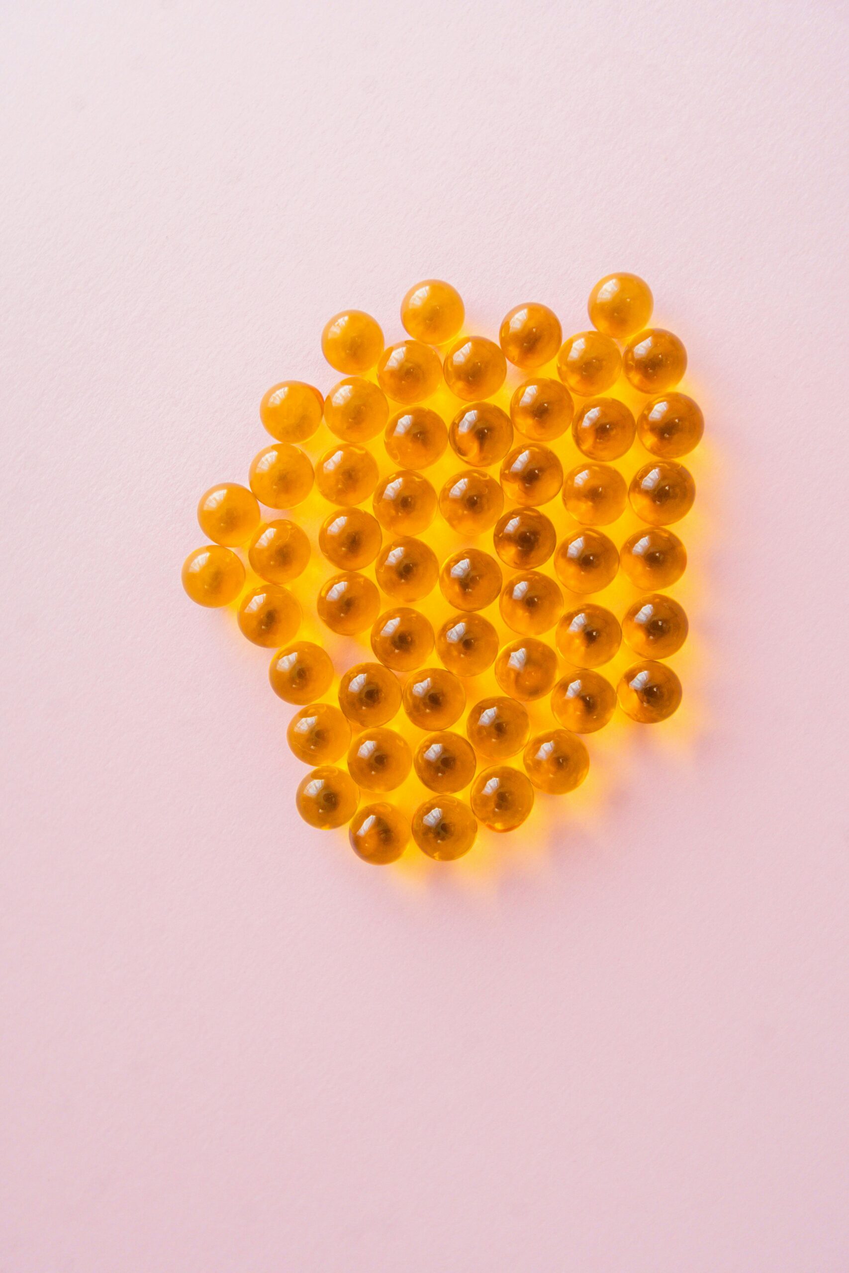 Close-up of yellow capsules on a pink background, showcasing health and vitality.