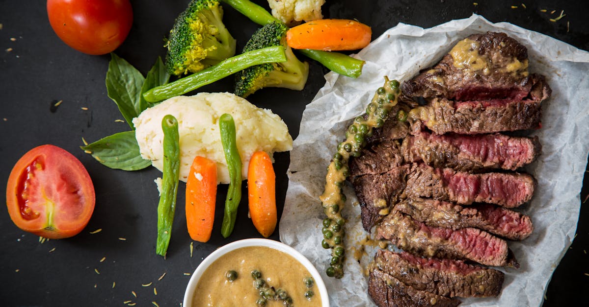 Grilled steak served with fresh vegetables and pepper sauce, presenting a colorful and appetizing meal.
