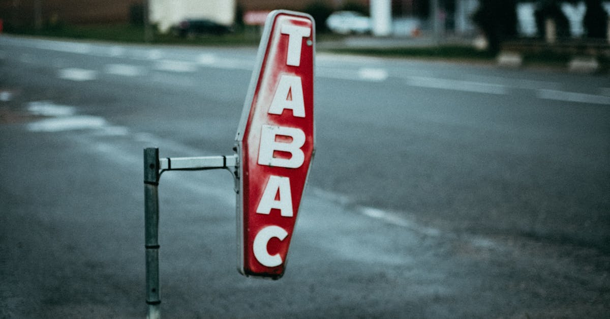 A vintage 'Tabac' sign on a street with blurred background, captured at dusk.
