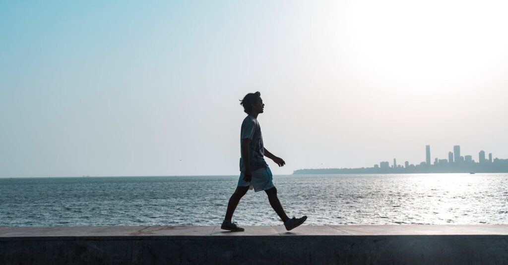 A silhouette of a man walking along the Mumbai coastline at sunset with a cityscape backdrop.