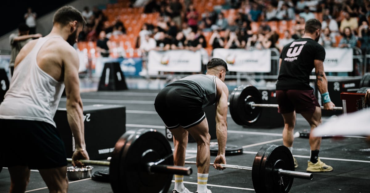 A group of athletes performing deadlifts during a competitive weightlifting event indoors.