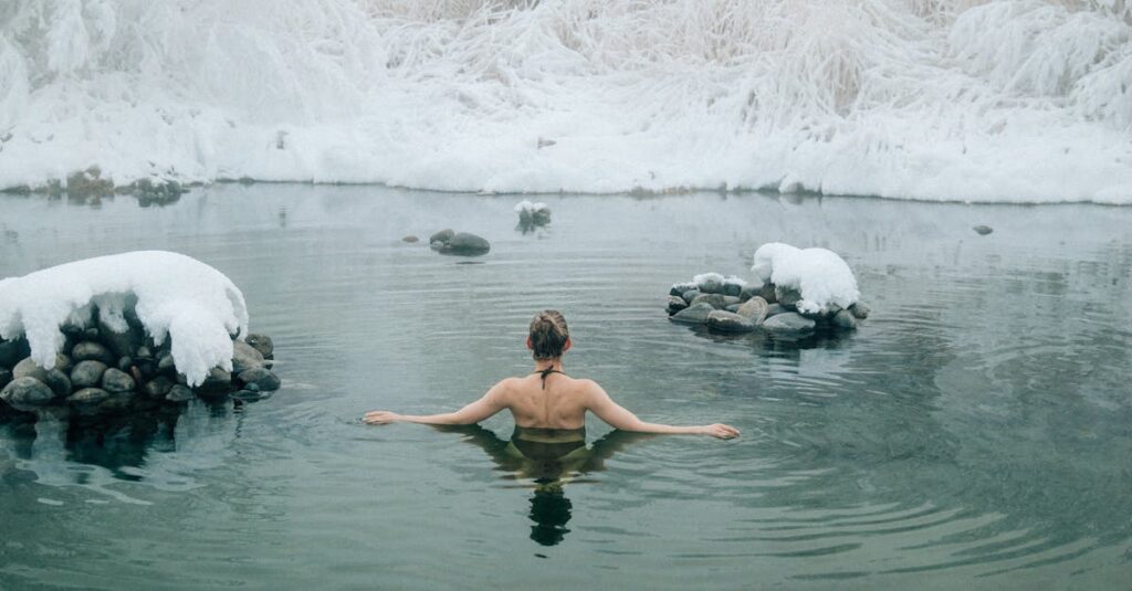 A young woman enjoying a swim in a tranquil winter lake surrounded by snow.