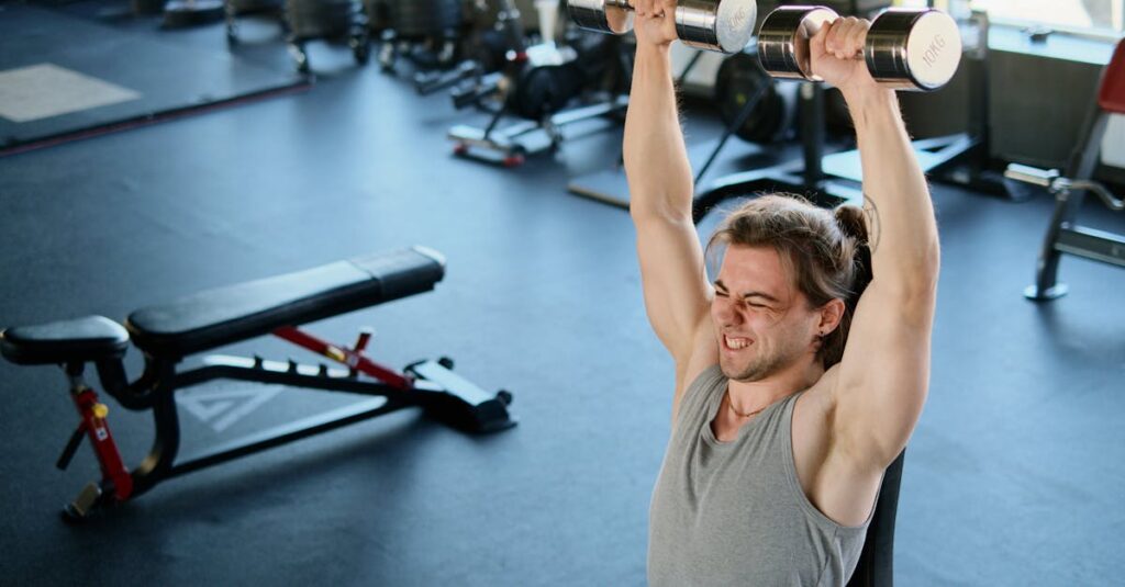 Man intensely lifting dumbbells in a modern gym, showcasing strength and endurance.