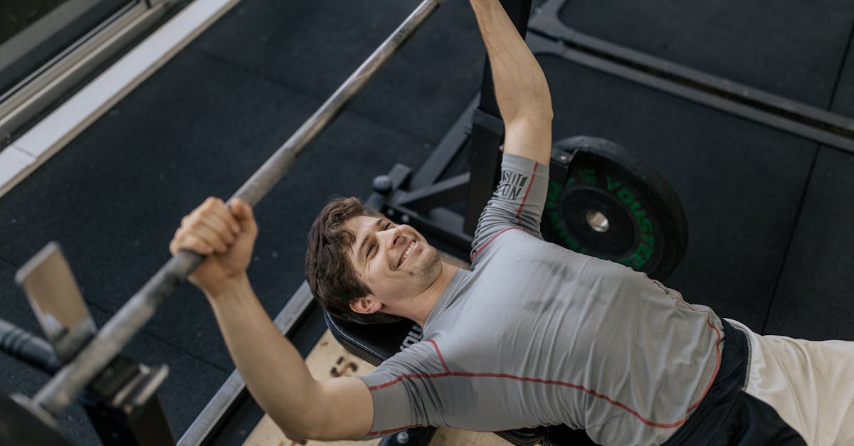 Adult man performing a barbell bench press in a modern gym, showcasing strength and fitness.