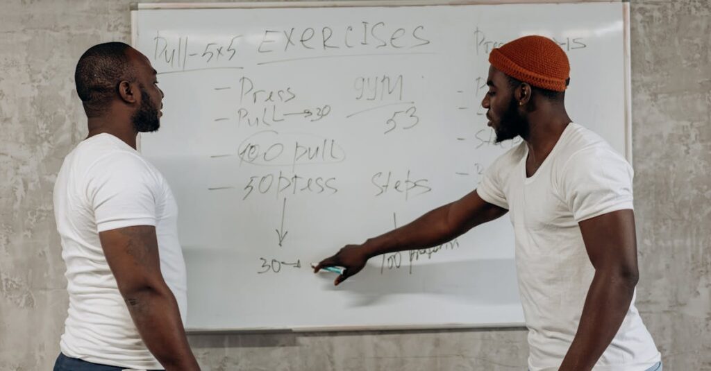 Two men discussing exercise routines on a whiteboard, planning gym workouts indoors.