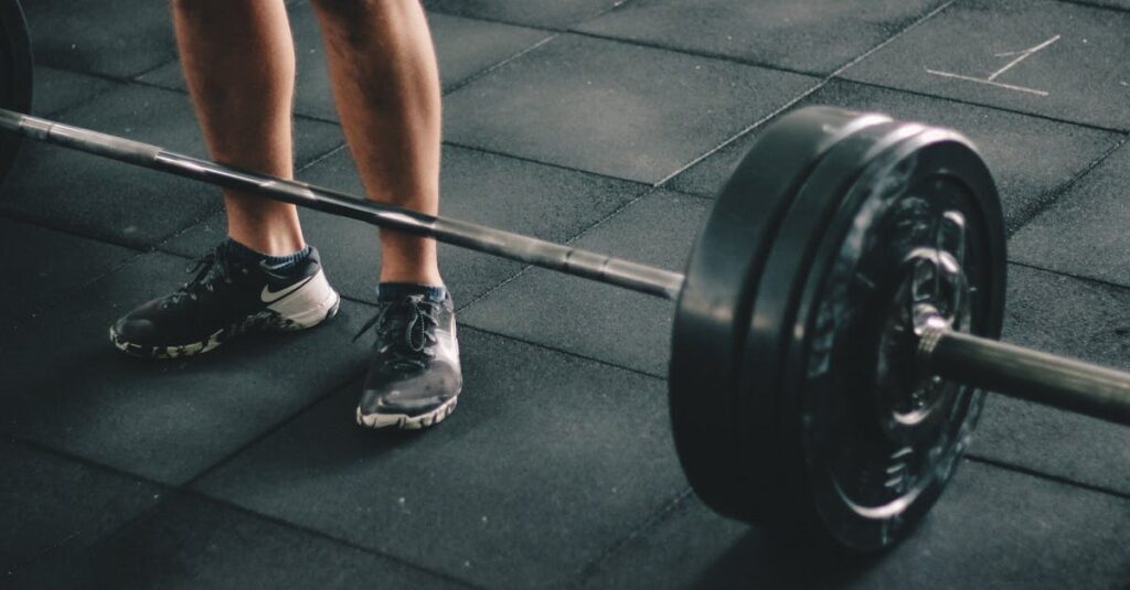 Close-up of a man deadlifting a heavy barbell in an indoor gym setting.