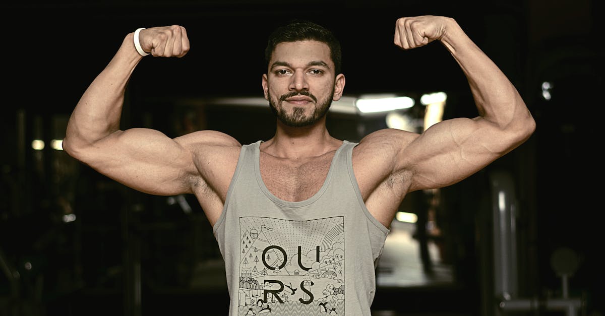 A fit man flexing his biceps in a gym environment, showcasing strength and fitness.
