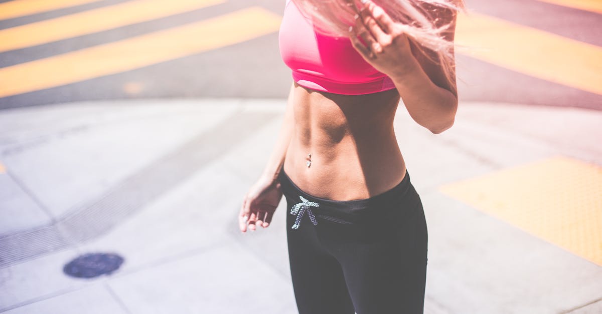 Athletic woman in pink activewear showing toned abs in urban San Francisco setting.