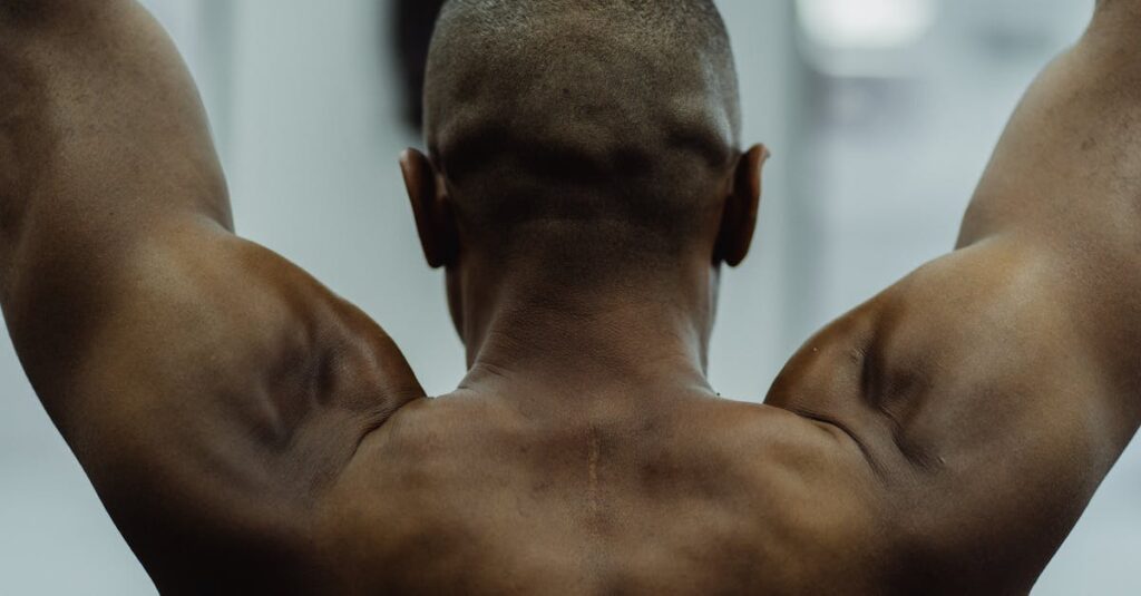 Shirtless man showing strength with visible muscles during workout, focus on back view.
