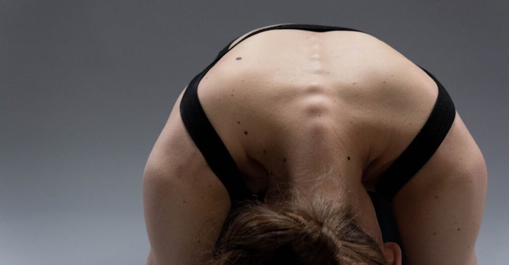 A woman performing a yoga pose that highlights her flexible back muscles in a studio setting.