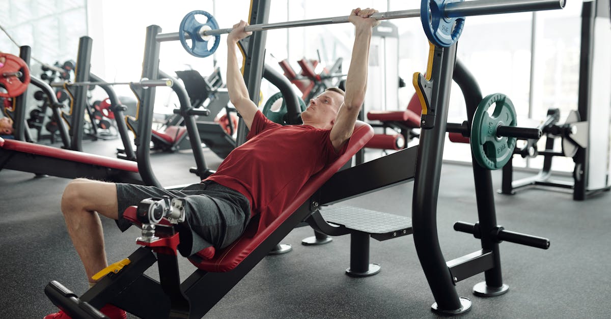 Un jeune homme effectue un exercice de développé incliné, banc incliné, à la barre en salle de sport.