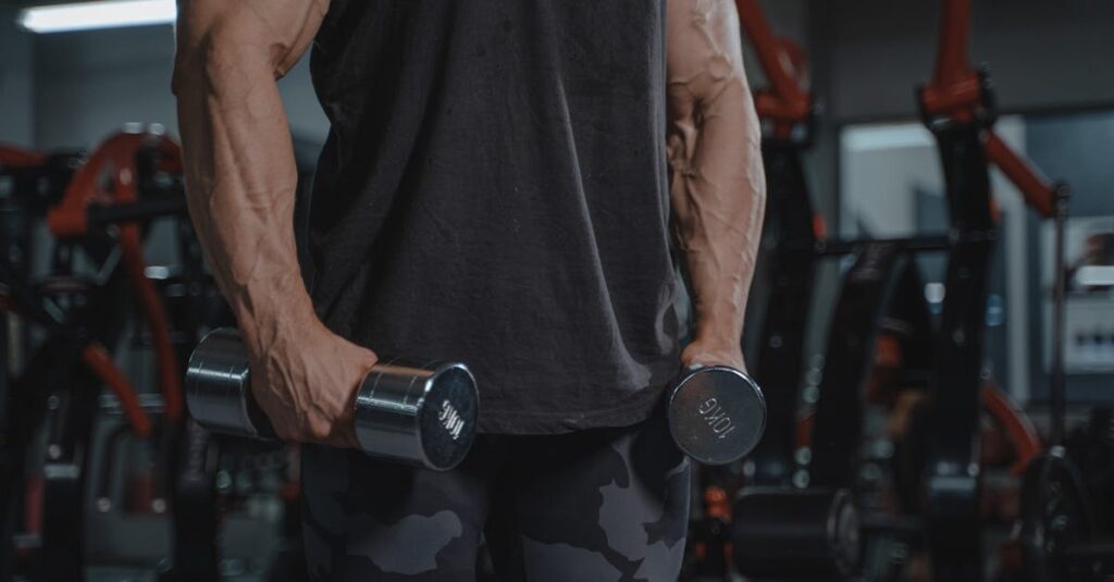 Jeune homme musclé s'entrainant en salle de sport, effectuant un mouvent de curl marteau en prise neutre.